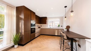 Une cuisine moderne avec des meubles en bois, un four encastré et un coin bar avec des tabourets.