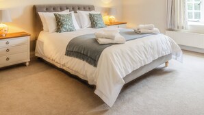 A neatly made bed with pillows, a bedside lamp, and a window with curtains.