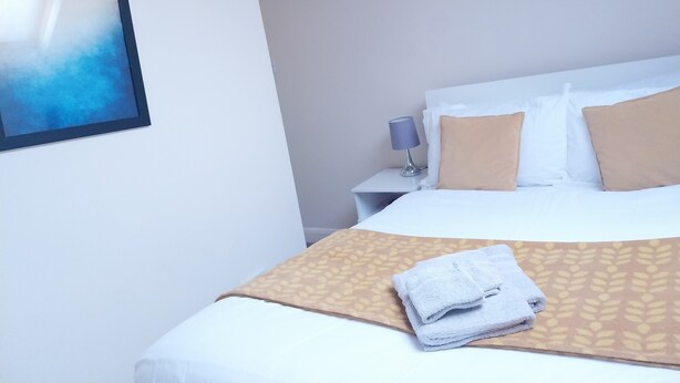 Une chambre d’hôtel avec un lit, une table de chevet avec une lampe et un tableau encadré au mur.