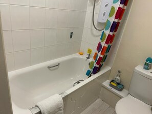 A bathroom with a white bathtub, a toilet, and a shower curtain with colorful circles. - Leeds Cute 1 bed Apt, Garden, Free Wifi & Parking (Leeds)