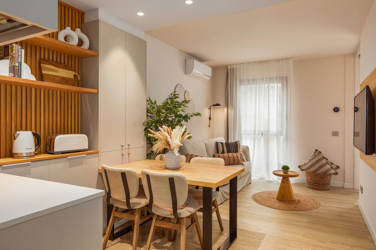 Eine moderne Küche mit Holzschränken, einem Esstisch mit Stühlen und einem eingebauten Backofen.