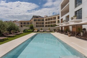 Una piscina al aire libre, sombrillas, tumbonas