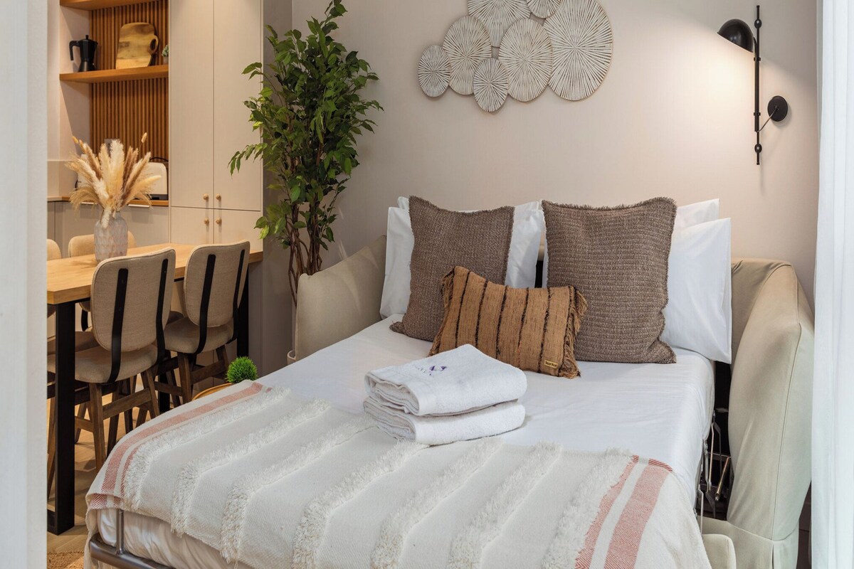 A bedroom with a bed, bedside tables, a wall-mounted air conditioner, and a decorative wall piece.