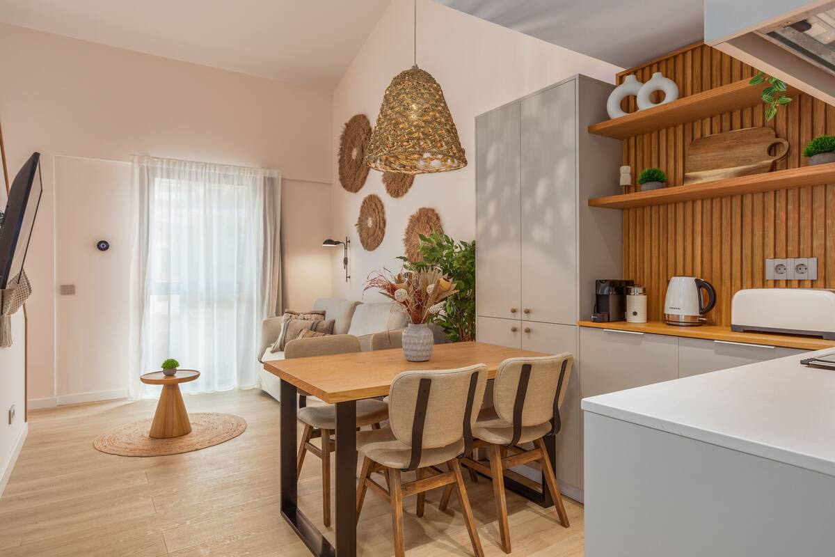Eine moderne Küche mit Holzausbau, einem Esstisch mit Stühlen und einer Hängeleuchte.
