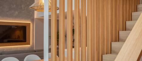 A modern interior with a wooden staircase, a dining area with a table and chairs, and a wall-mounted light fixture.