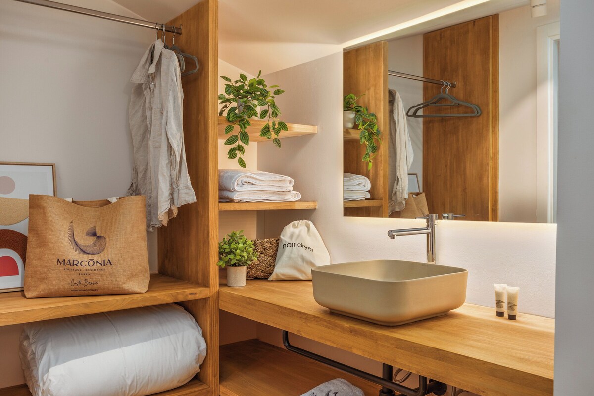Un baño moderno con tocador de madera, un espejo grande, un lavamanos y un perchero para toallas.