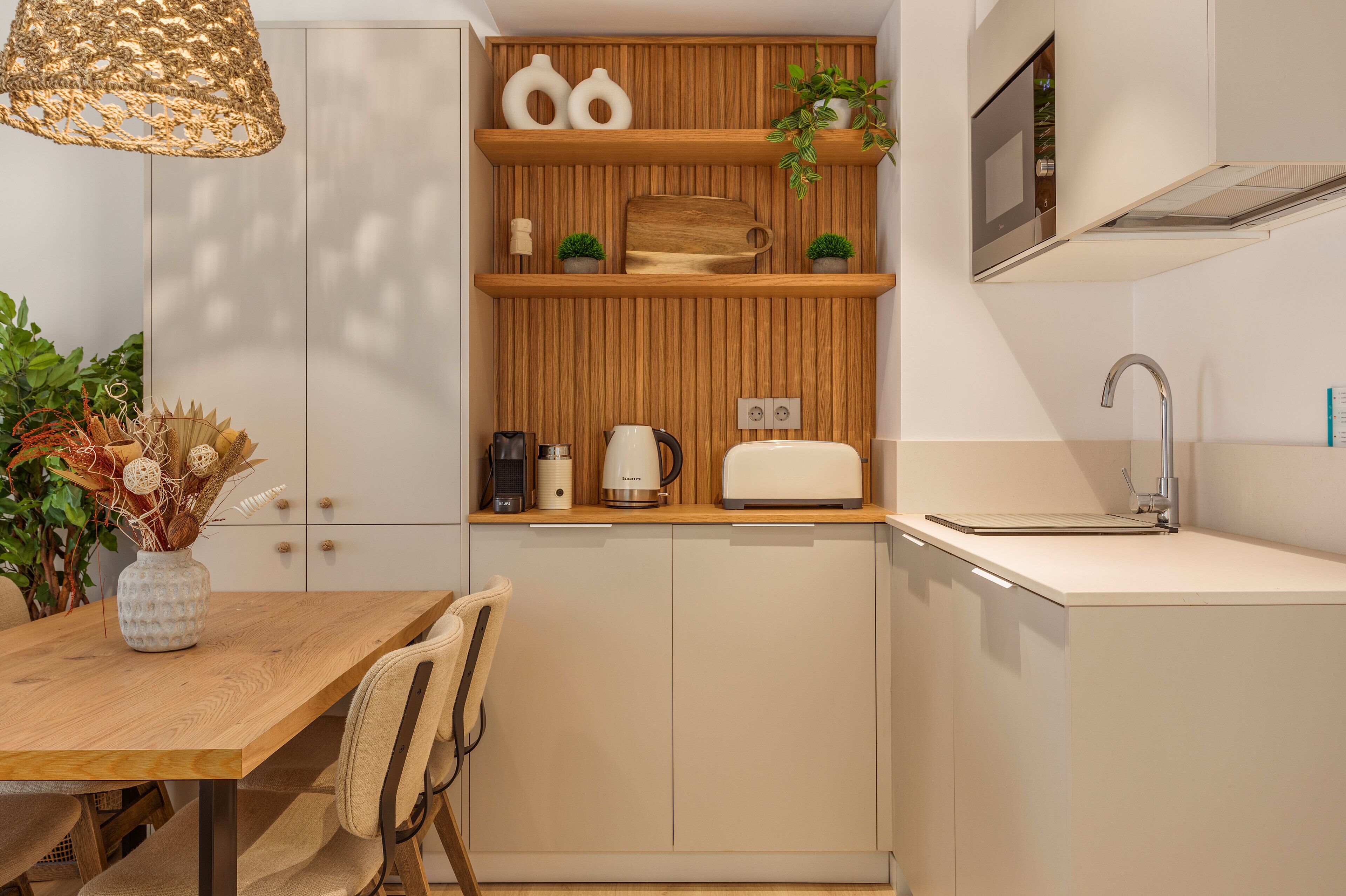 Una cocina pequeña con estantes de madera, cafetera, tostadora y pileta.