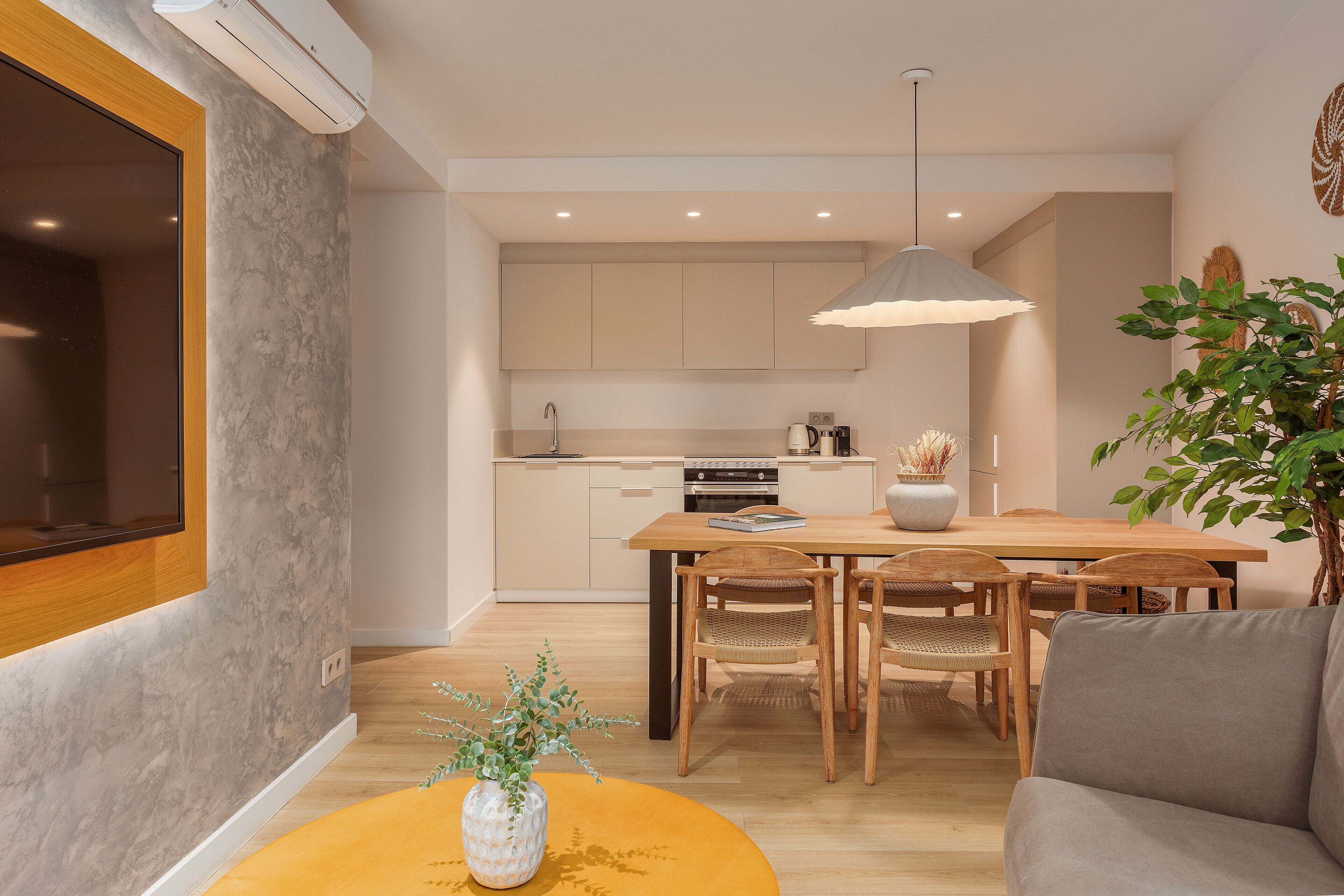 Une cuisine moderne avec un coin repas, des meubles en bois et une plante en pot.