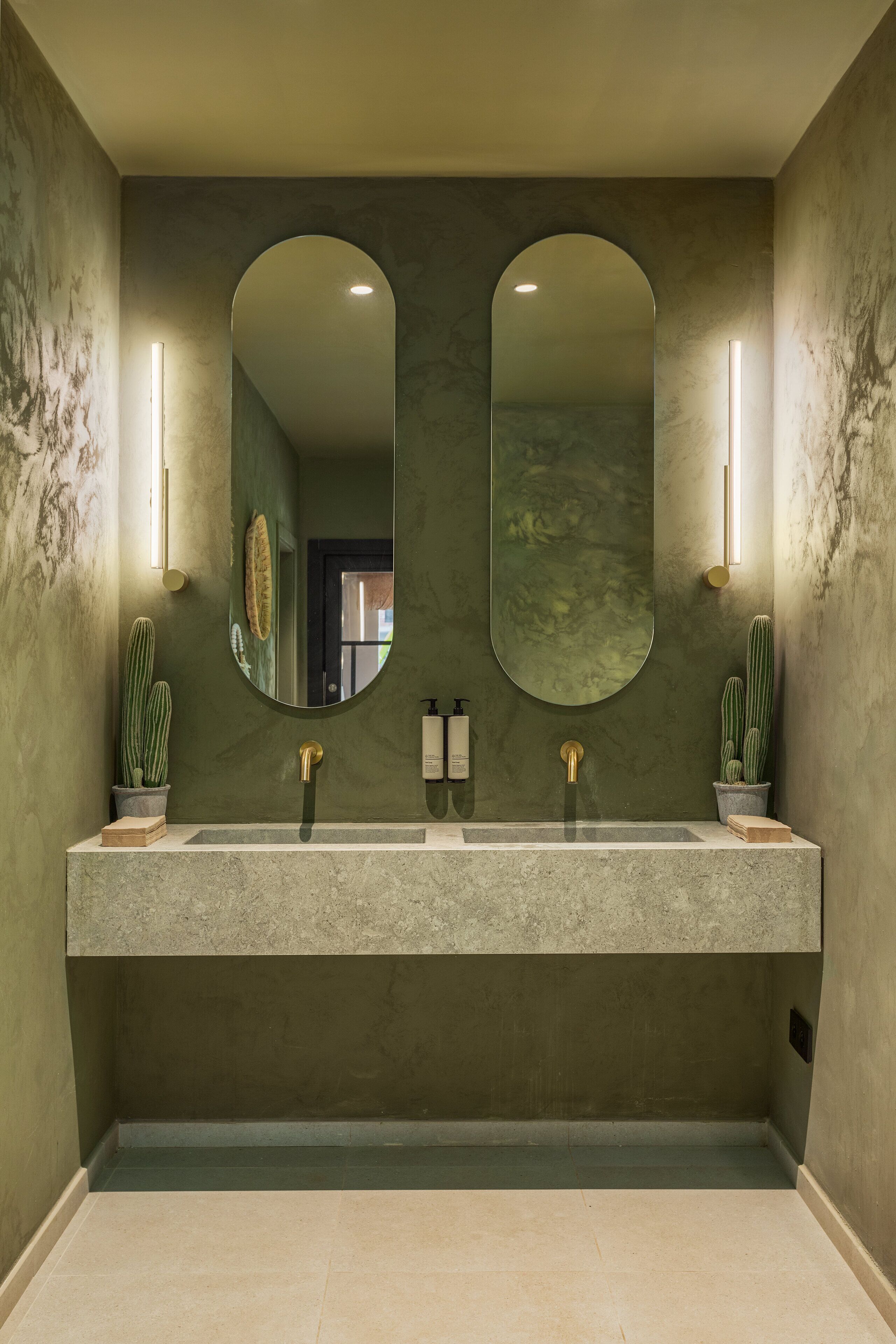A bathroom with two sinks, a large mirror, and wall-mounted lights.