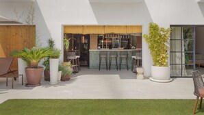Un patio al aire libre moderno con barra, asientos y plantas en macetas.