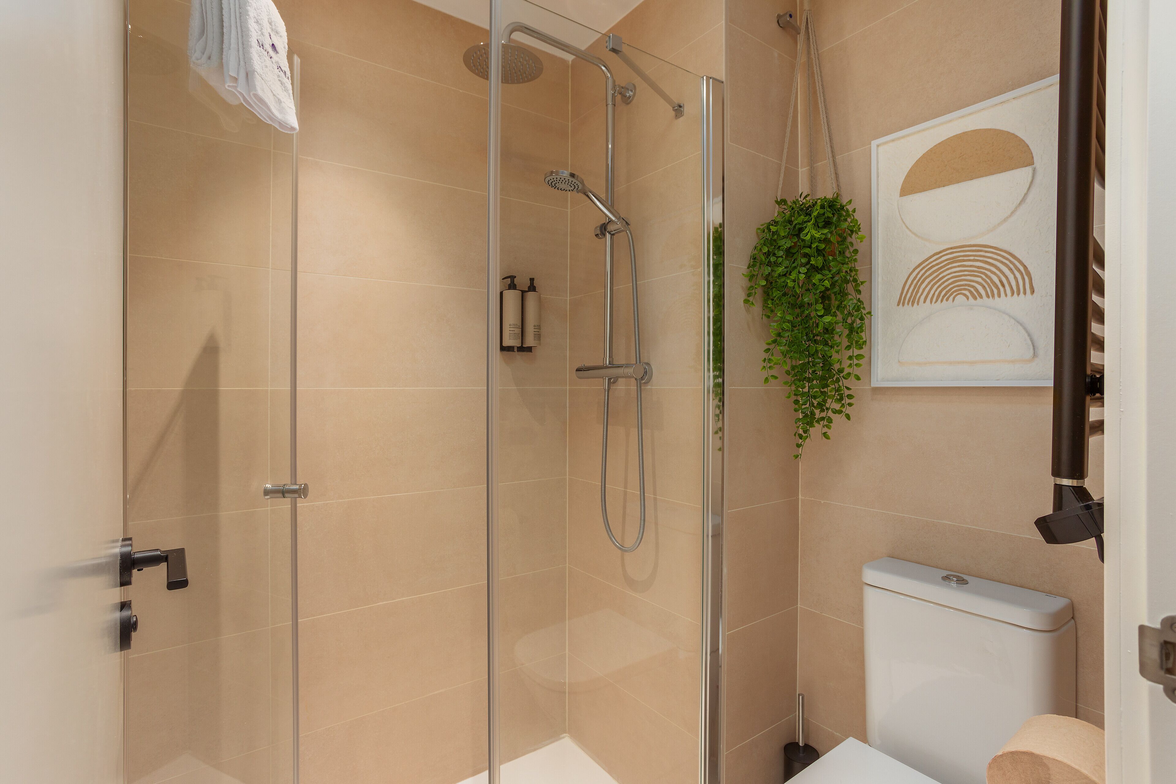 Un baño moderno con ducha separada por mampara de vidrio, inodoro y lavabo.