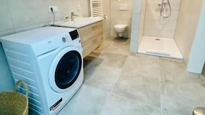 A modern bathroom with a washing machine, a toilet, and a shower area. - 2 bedrooms in the heart of Limpertsberg (Luxembourg City)