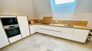 A modern kitchen with white cabinets, a built-in oven, a sink, and a wooden countertop. - 2 bedrooms in the heart of Limpertsberg (Luxembourg City)