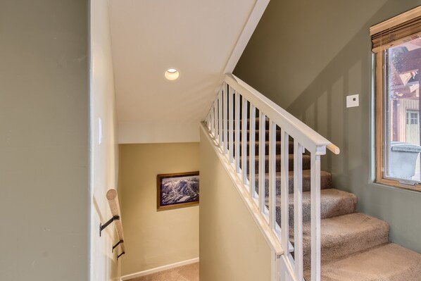 Eine Treppe mit weißen Geländern und beige belegten Stufen.