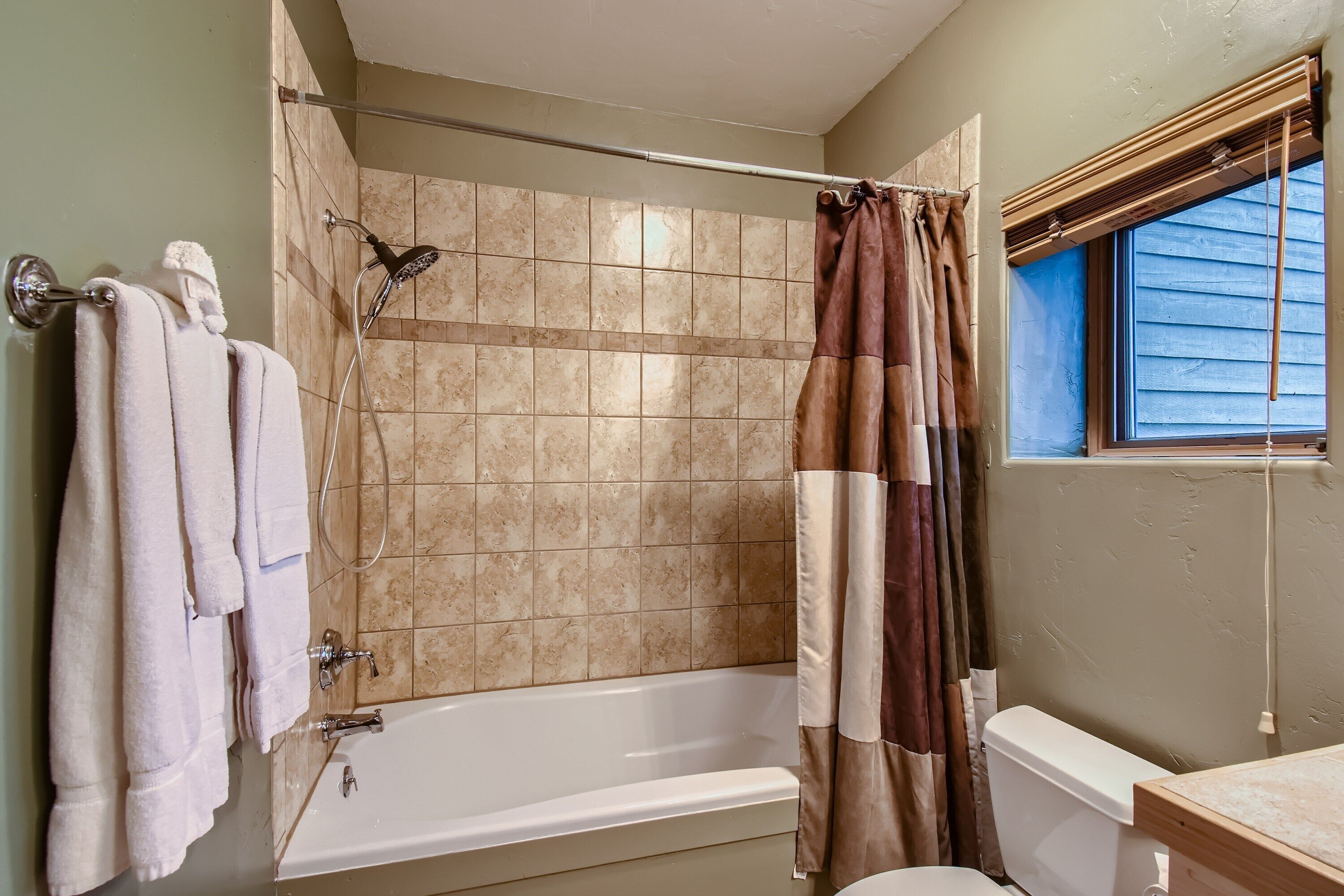 A bathroom with a bathtub, shower, and toilet.