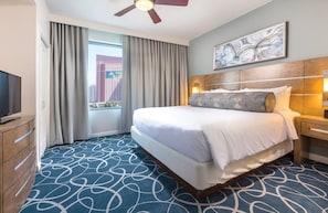 A hotel room with a large bed, a ceiling fan, a television, a nightstand, and a view of a cityscape through the window. - Las Vegas | Couples Skyline Lights & Strip Fun | Pool + Cabanas (Las Vegas)