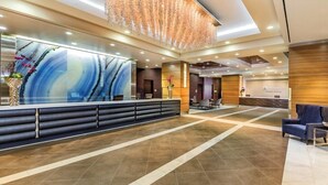A modern reception area with a long counter, seating, and a decorative ceiling. - Wyndham Desert Blue - 1 Bedroom Suite (Las Vegas)