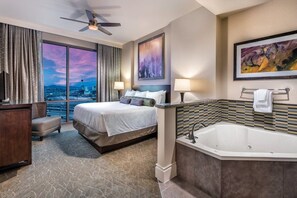 Ein Hotelzimmer mit einem großen Bett, einer Badewanne, einem Schreibtisch und Blick auf die Stadtlandschaft.