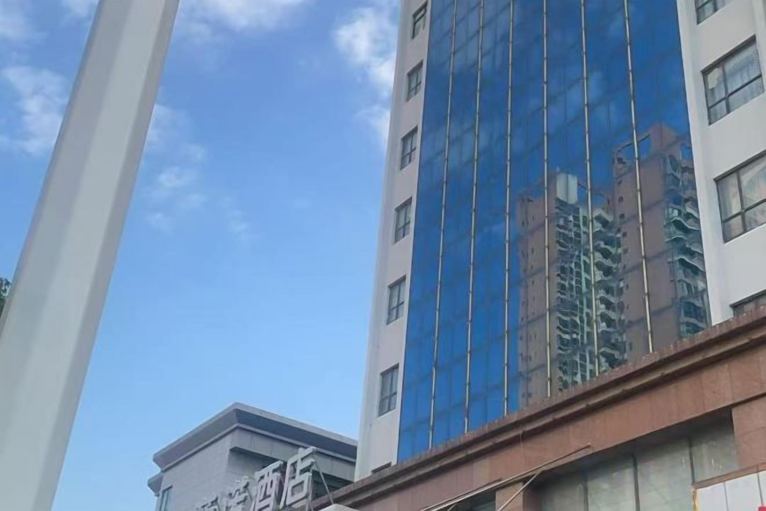 Un edificio de varios pisos con fachada de vidrio reflectante y un letrero que indica que es un hotel.