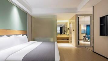 Ein Hotelzimmer mit einem großen Bett, einem begehbaren Kleiderschrank, einem Badezimmer mit Spiegel und einem an der Wand befestigten Fernseher.