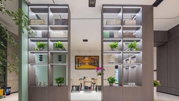 A modern interior with two tall shelving units, a dining area, and a painting on the wall.