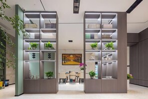 A modern interior with two tall shelving units, a dining area, and a painting on the wall. - Haiyi Fino Hotel (Swan Lake Branch） (Jingmen)