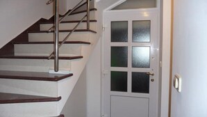 A staircase with wooden steps and metal railings leading to a white door with frosted glass panels.