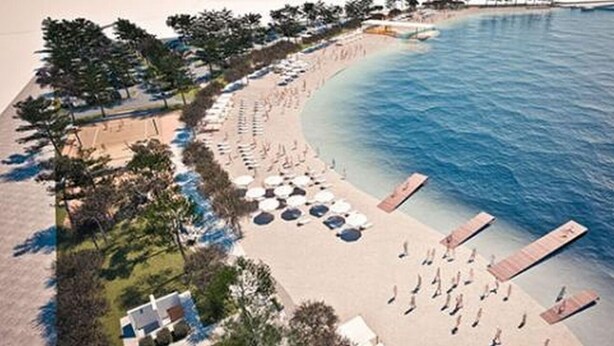 An aerial view of a beach with rows of sun loungers and umbrellas, a wooden pier, and a clear blue sea.