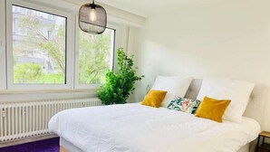 Ein Schlafzimmer mit Bett, Fenster, Heizkörper und einer Pflanze.