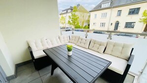 Ein Balkon mit einem schwarzen Tisch und weiß gepolsterten Sitzgelegenheiten.