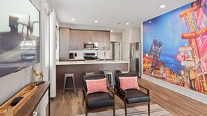Een moderne keuken met een centraal eiland, barstoelen en een groot stadsgezicht op de muur.