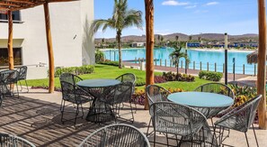 A patio with outdoor seating and a view of a swimming pool.