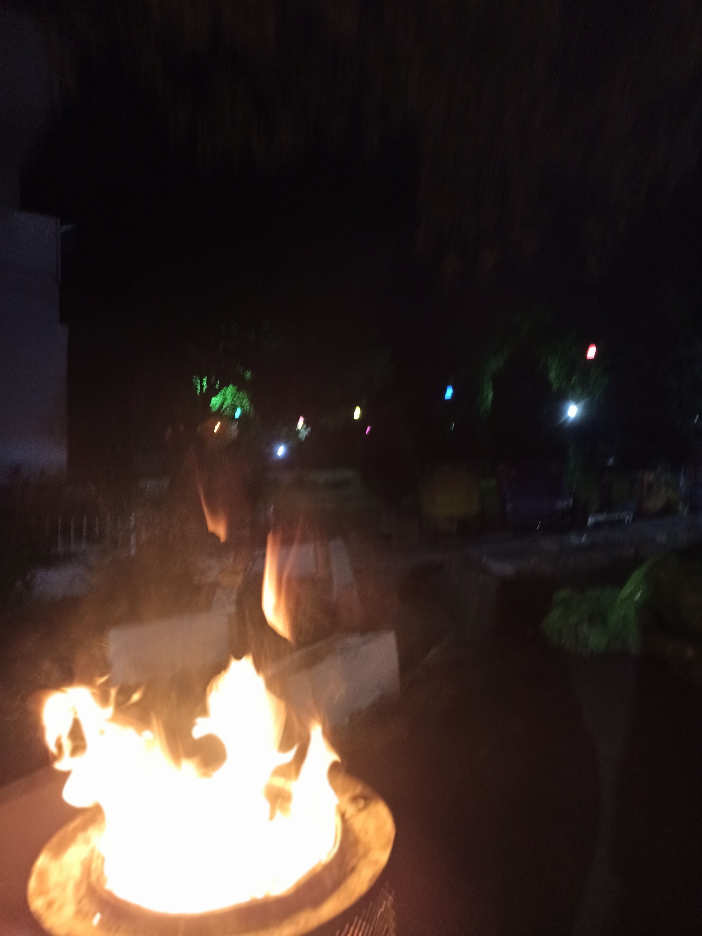 A fire in a dark outdoor setting, possibly a courtyard or garden area.