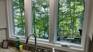 A kitchen with a double sink, granite countertop, and a window with a view of trees. - 4BR Lake House w/ Private Dock, Hot tub, and Lake Views! (Blairsville)