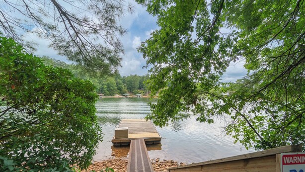 A wooden dock leading to a calm lake surrounded by lush greenery. - 4BR Lake House w/ Private Dock, Hot tub, and Lake Views! (Blairsville)