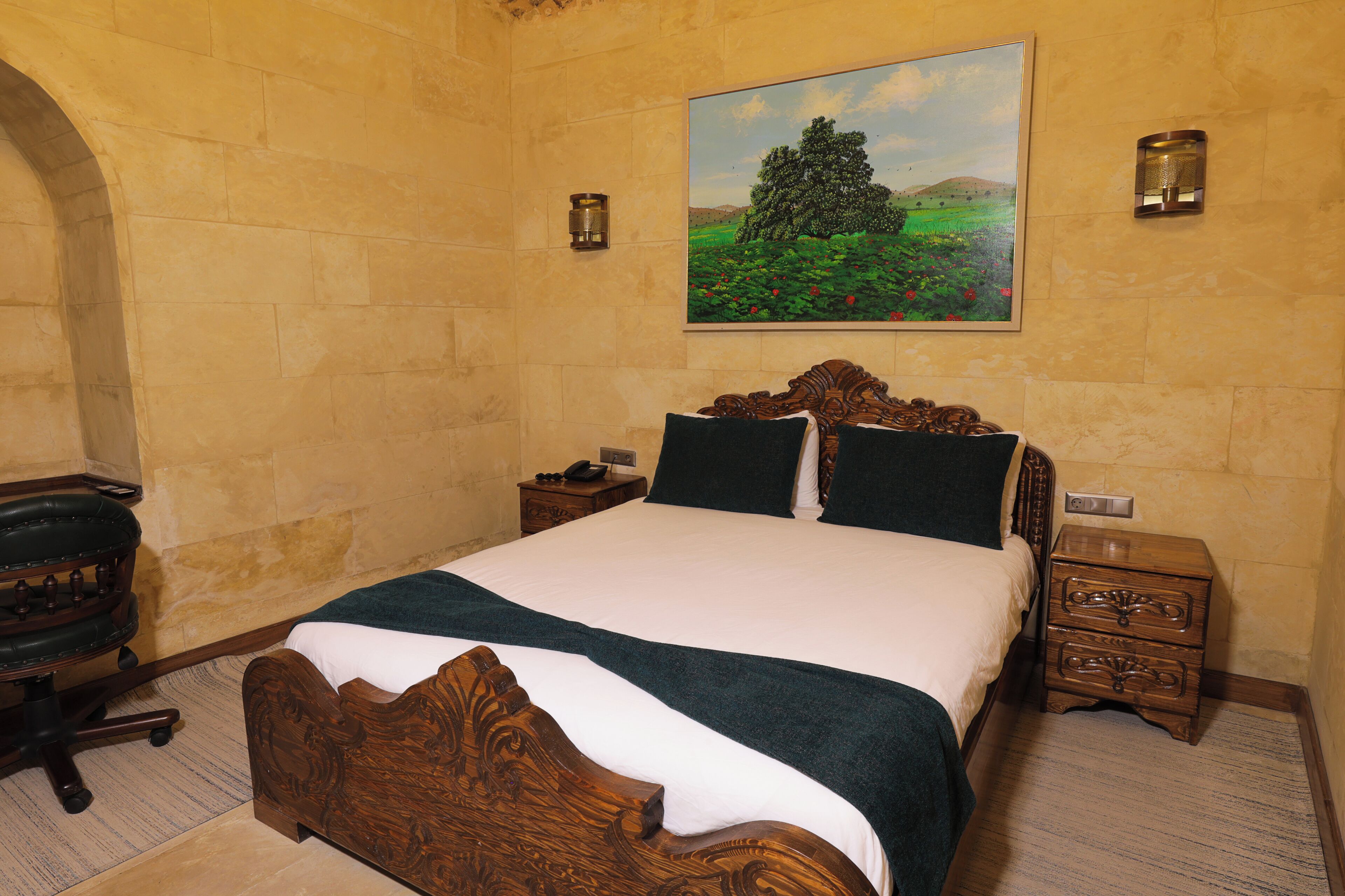 A bedroom with a wooden bed, a nightstand, a desk, and a chair.