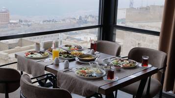 A dining table with various dishes and drinks, set against a city view.