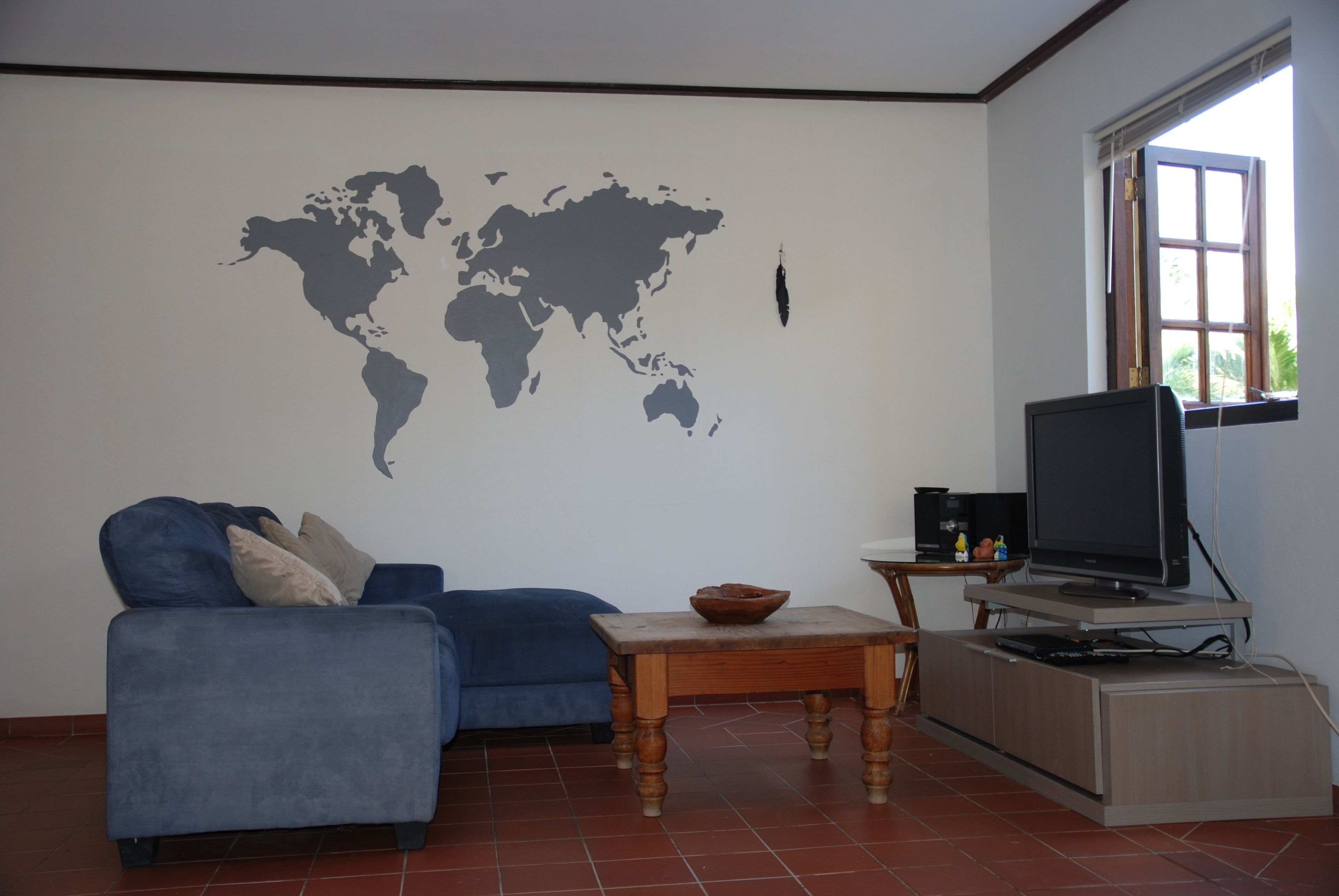 A living room with a sofa, a coffee table, a TV, and a world map on the wall.
