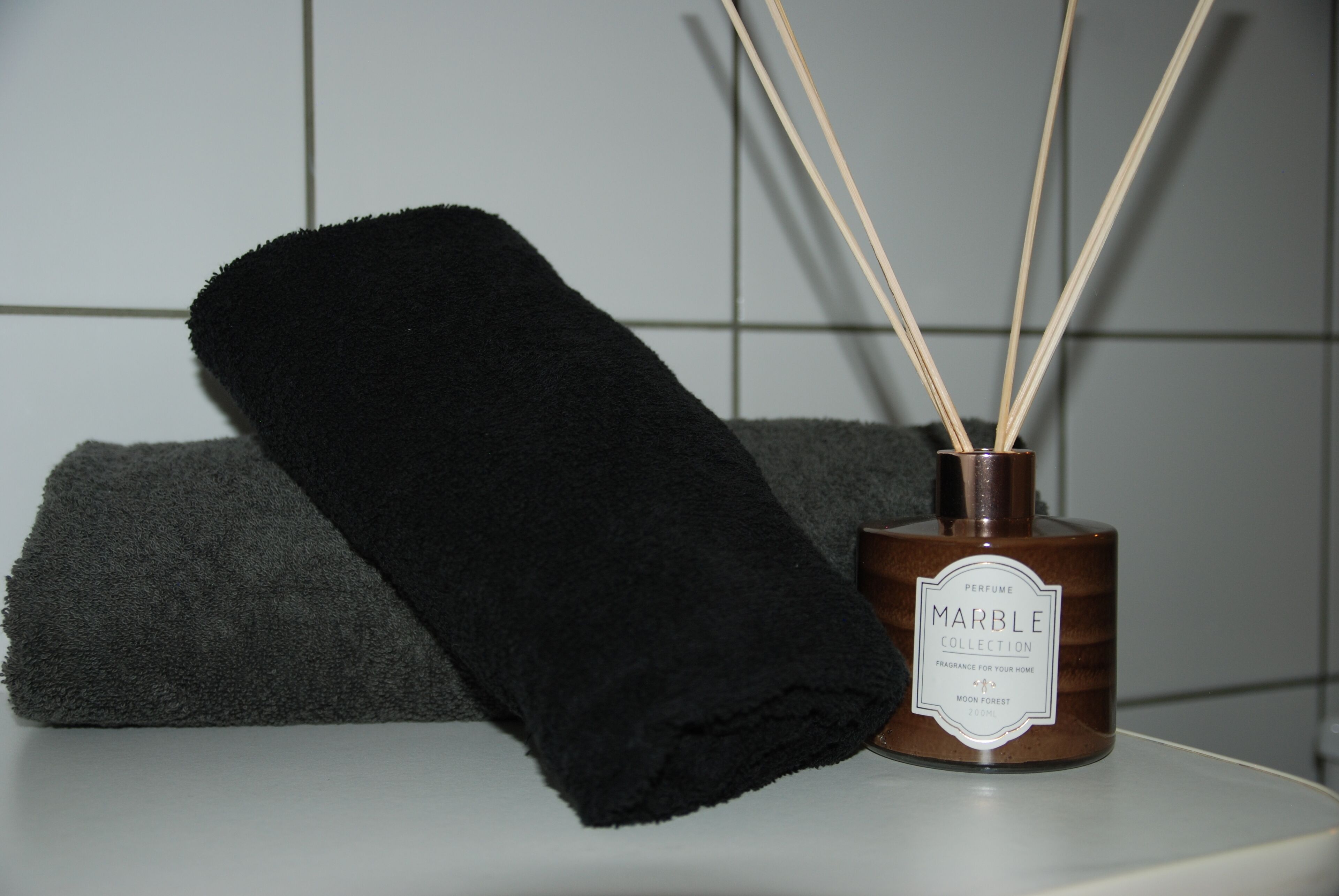 Een donkere handdoek en een parfumfles met rietstengels.