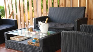 A patio area with wicker furniture, a glass-top table, and a wooden fence in the background. - Mirador Apartments (Willemstad)