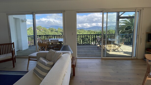 Ein geräumiges Wohnzimmer mit einem großen Schiebeglastür, die auf eine Terrasse im Freien führt.