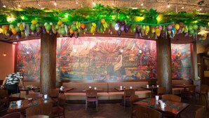 An indoor dining area with booths, tables, and chairs. There is a large mural on the back wall. - Ko Olina | Romantic Disney Retreat | Lagoon + Pool (Kapolei)