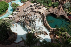 Luchtbeeld van een resort met een centraal gelegen zwembad, diverse ligbedden en een rotsachtig landschap.