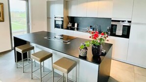 A modern kitchen with a central island, bar stools, a sink, and a view of the outdoors. - Luxury 3 bedrooms- Terrace and Parking (Bertrange)