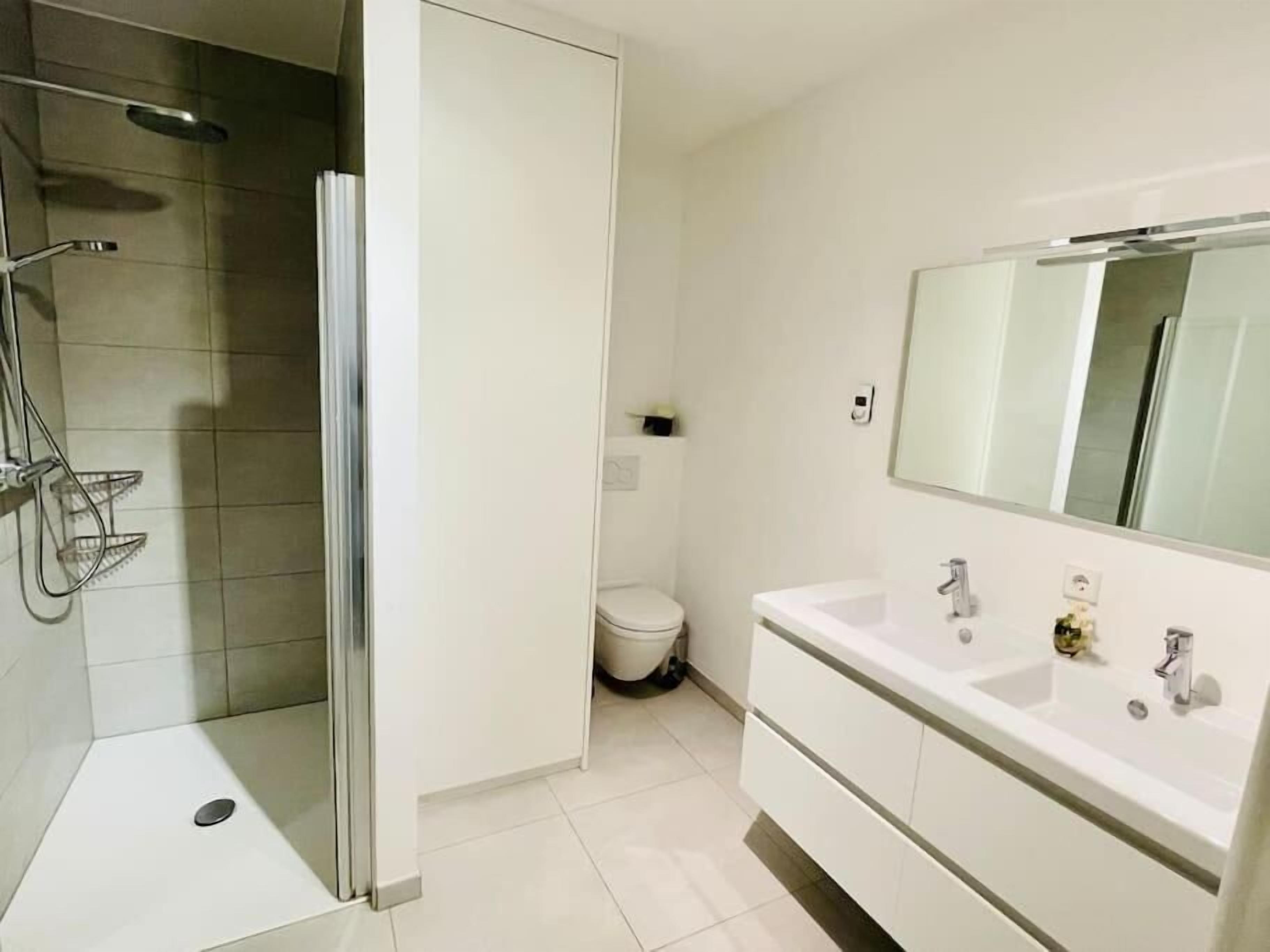 Une salle de bain moderne équipée d’une douche, de toilettes et d’un meuble-lavabo.