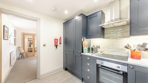 Eine moderne Küche mit dunklen Schränken, einem eingebauten Backofen und einer Spritzschutzwand.