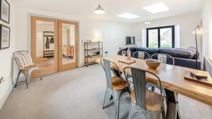 Ein moderner Wohnraum mit Essbereich, einer Couch und Blick durch ein großes Fenster.