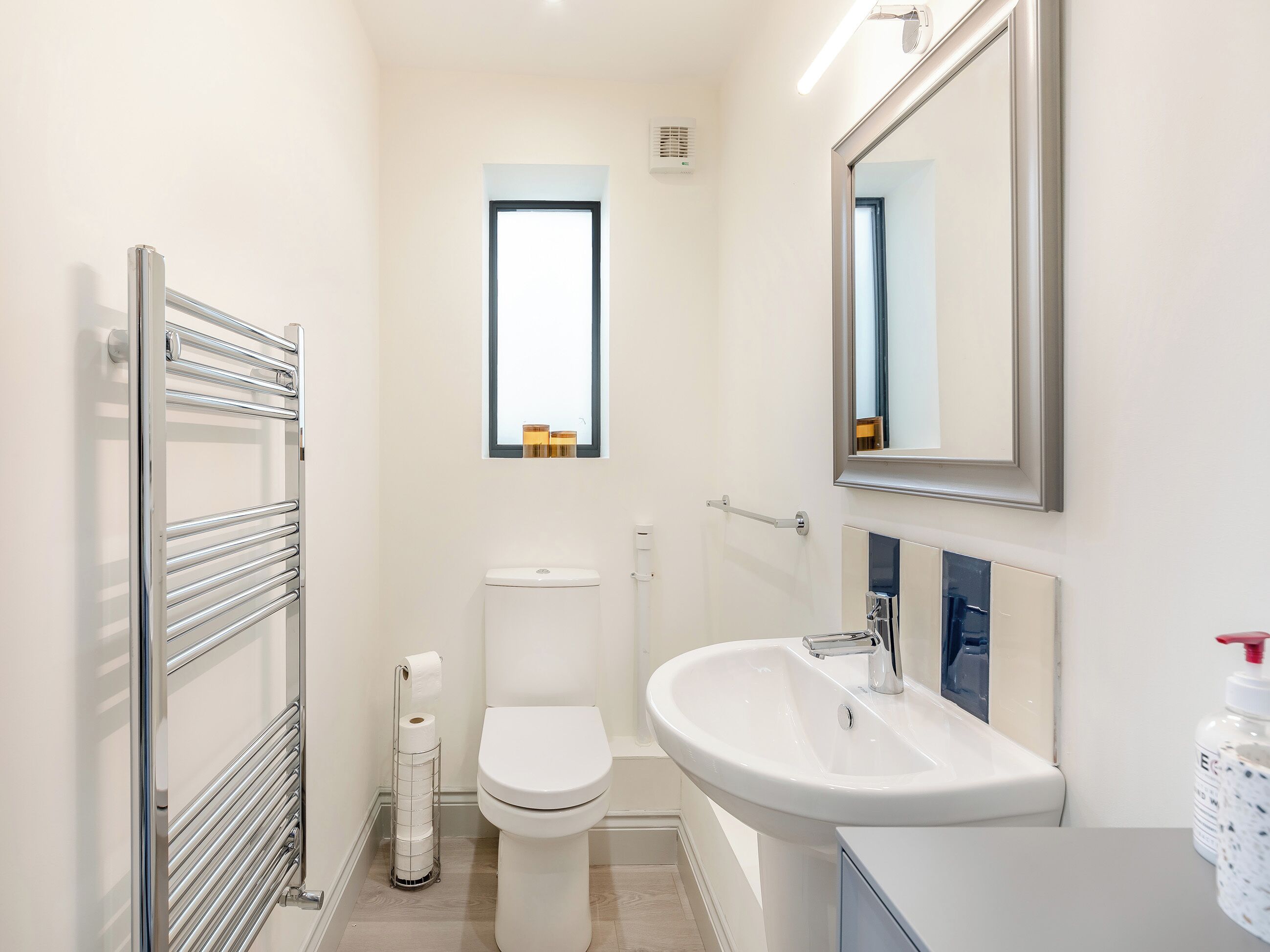 A modern bathroom with a toilet, a sink, a mirror, and a towel rack.