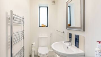 A modern bathroom with a toilet, a sink, a mirror, and a towel rack.