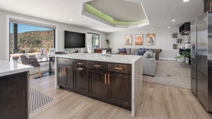 A modern kitchen with a large island, dark cabinetry, and a built-in oven.